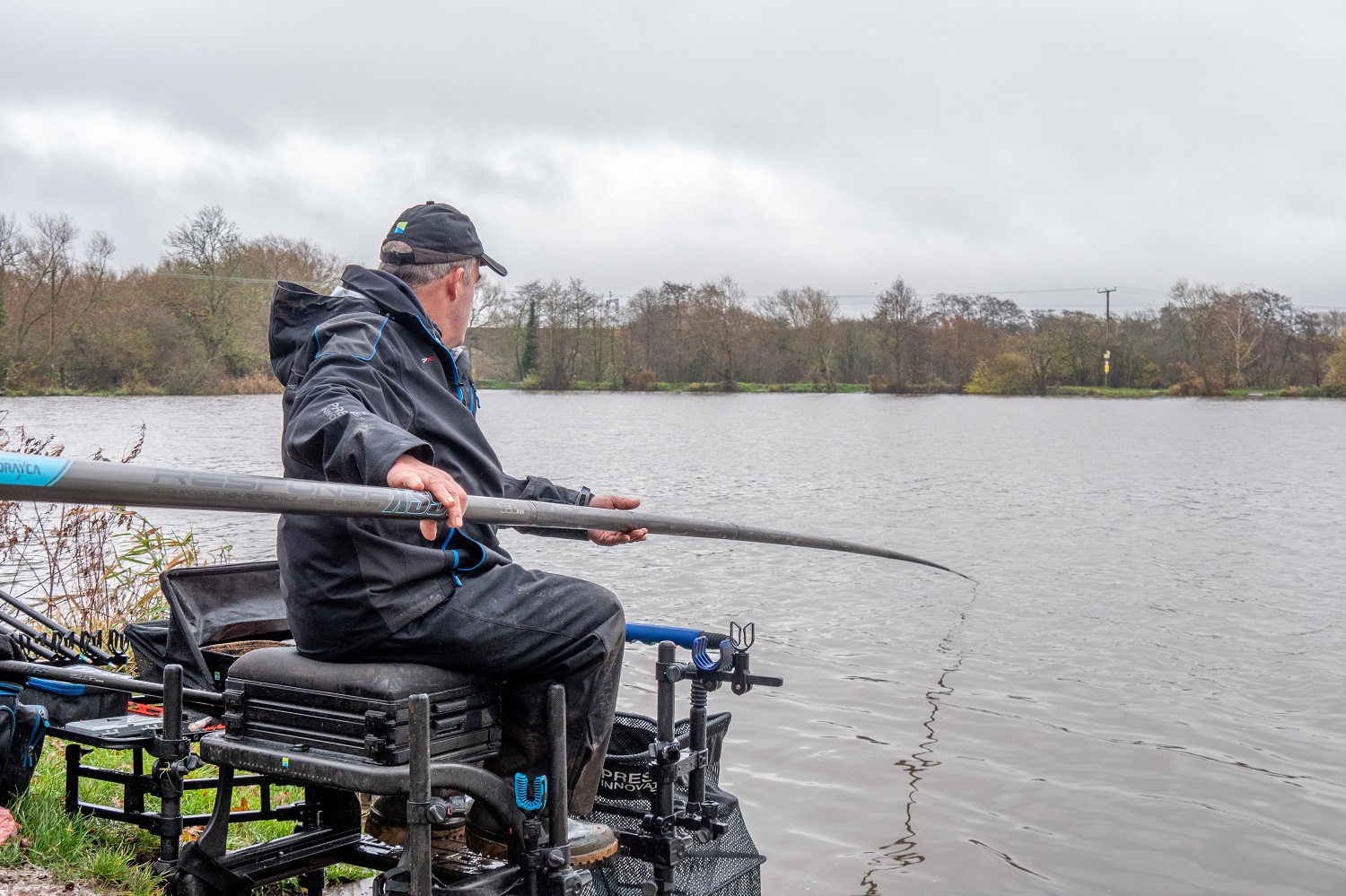 Des holding a fishing pole by the water